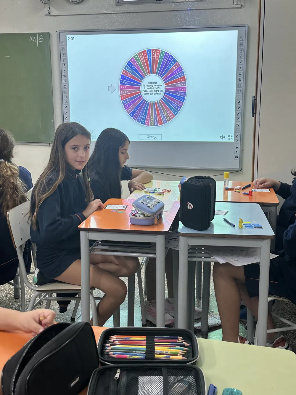 Alumnas de primaria resolviendo tablas de multiplicar con la pizarra digital del aula