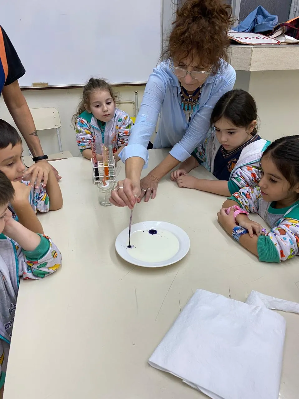 Docente y niños del jardín observando un experimento con colorante y leche